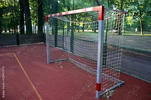 public multifunctional city playground with tartan surface in the park is used to play basketball football floorball goals baskets green safety nets mantineles of wood and game lines of yellow and  photo