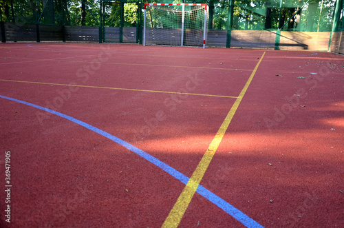 public multifunctional city playground with tartan surface in the park is used to play basketball football floorball goals baskets green safety nets mantineles of wood and game lines of yellow and  photo