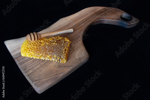 Raw honeycomb on cutting board. Black background,copy space, natural product