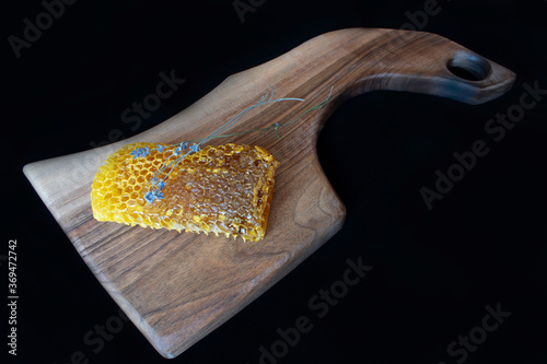 Raw honeycomb on cutting board. Black background,copy space, natural product