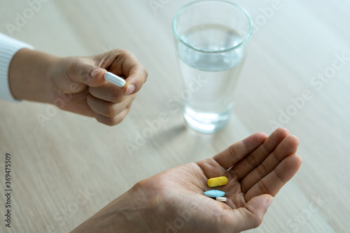a woman holding a food supplement or medication with a glass of water on the table. Medical concepts and health care, illness