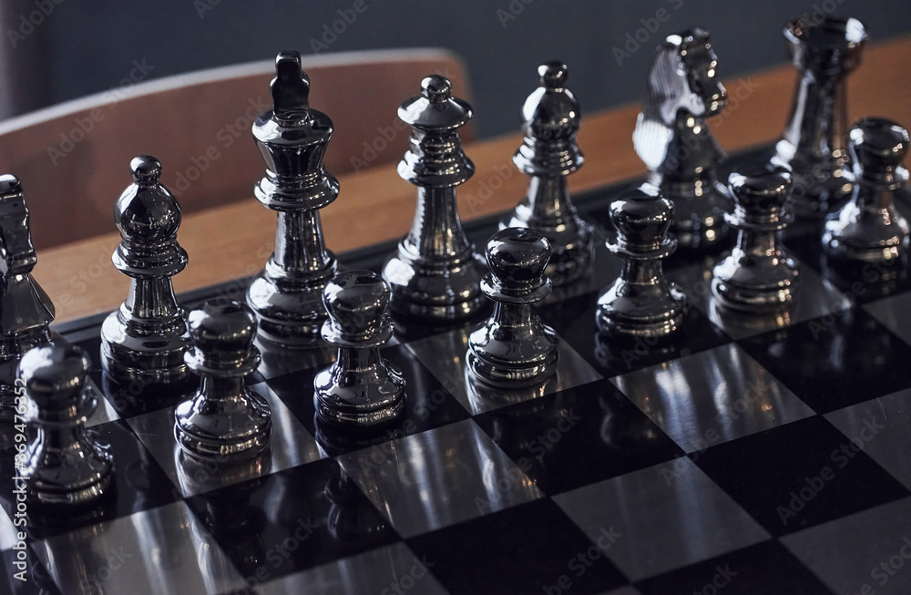 Chess board with metal figures on it indoors on the table at daytime Chess board with metal figures on it indoors on the table at daytime