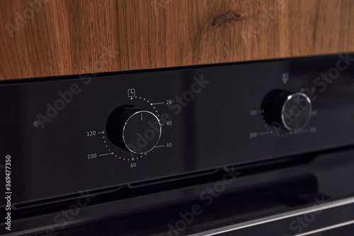 Close up view of gas stove knobs indoors in the kitchen. Wooden material