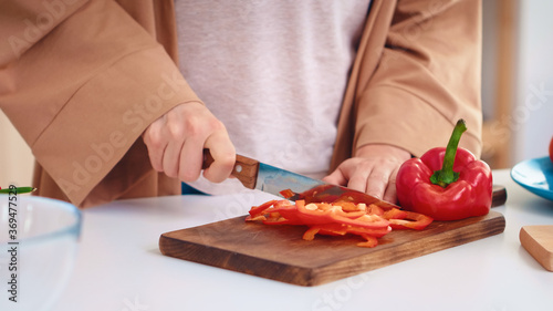 Wife hands close up slicing pepper on wooden cutting board in kitchen. Cooking preparing healthy organic food happy together lifestyle. Cheerful meal in family with vegetables