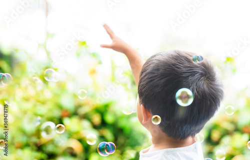 外でシャボン玉を掴もうと手を空に伸ばしている子供　空に向かって手を伸ばす子供