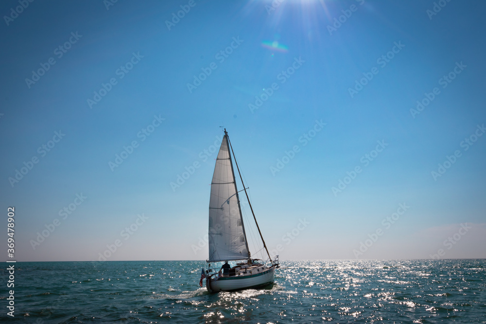 Naklejka premium sailboat on the sea with the sun barely in view