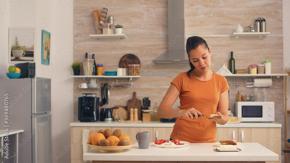 Woman spreading butter on toasted bread for breakfast. Knife smearing soft butter on slice of bread. Healthy lifestyle, making morning delicious meal in cozy kitchen. Traditional tasty lunch Woman spreading butter on toasted bread for breakfast. Knife smearing soft butter on slice of bread. Healthy lifestyle, making morning delicious meal in cozy kitchen. Traditional tasty lunch
