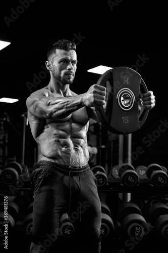 Portrait of bodybuilder holding weights straight out.
