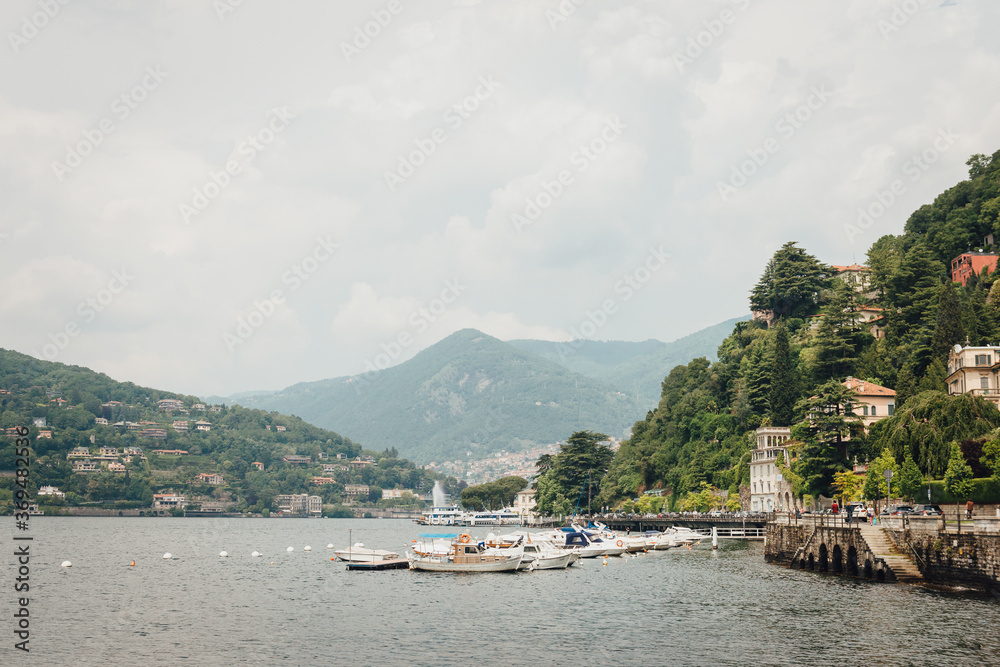 Lake Como view from Como сity promenade on a cloudy day. Boats and yacht on the water