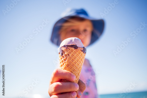 Happy girl child eating icecream in summer on a beach outdoors.