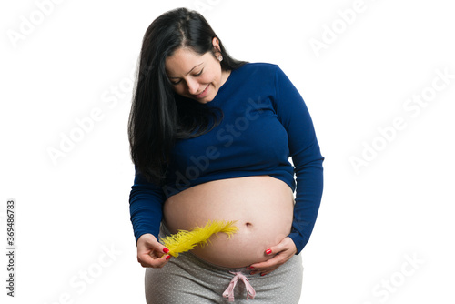 Happy future mother touching her tummy with yellow feather photo
