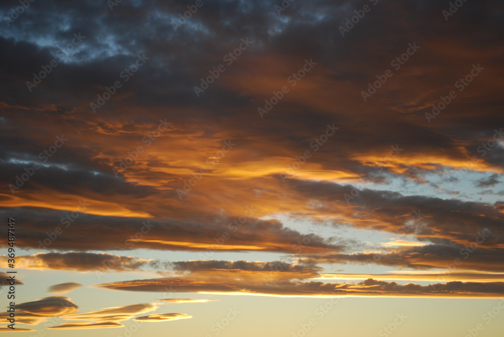 Dramatic sky clouds. Orange lenticular clouds. Sunset. South Patagonian sky.