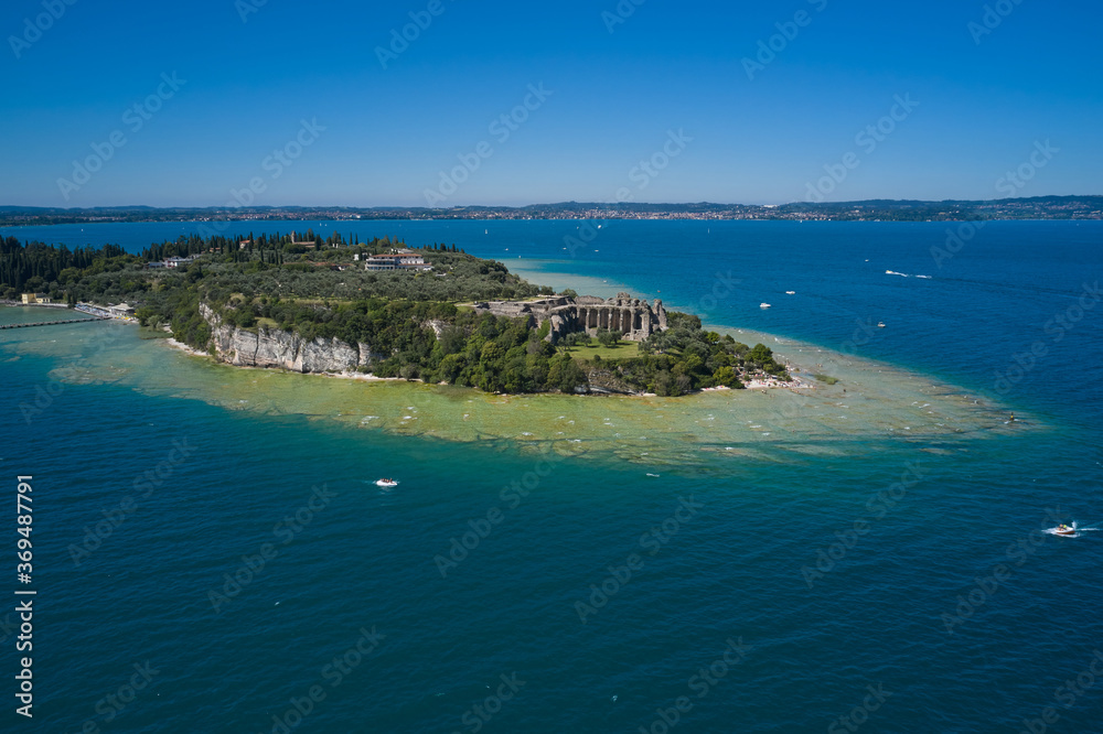 Archaeological site of Grotte di Catullo. Sirmione island aerial view. Garda lake, Sirmione, Italy. Aerial view on Grotte di Catullo. Sun reflections in water