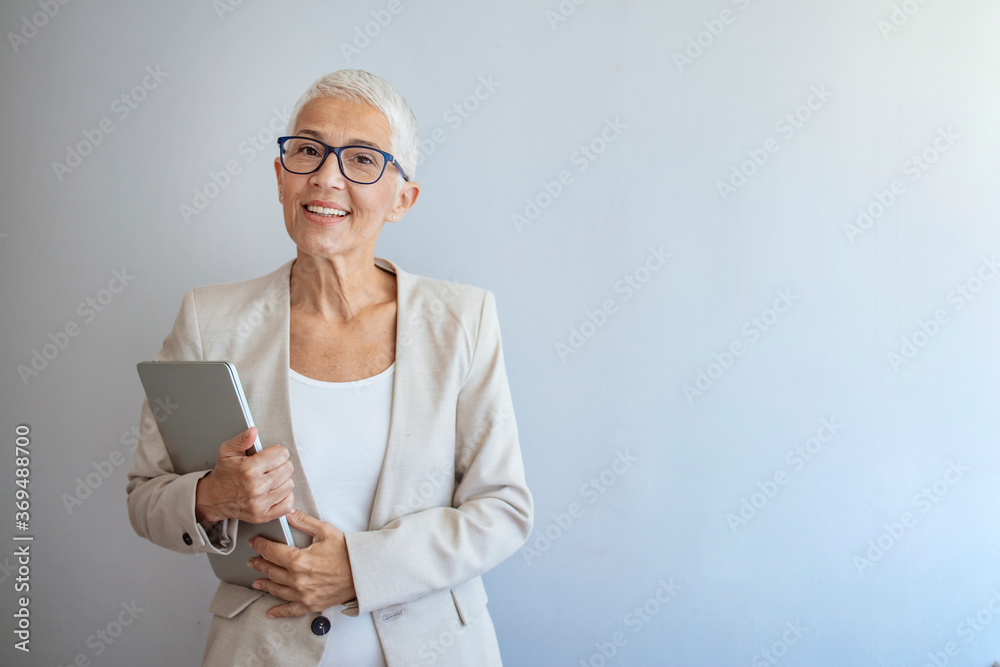 Portrait of elegant senior businesswoman standing in her office, smiling at the camera. Portrait of a confident mature businesswoman. Successful smiling senior woman with toothy smile Portrait of elegant senior businesswoman standing in her office, smiling at the camera. Portrait of a confident mature businesswoman. Successful smiling senior woman with toothy smile