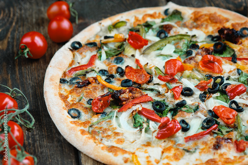 Delicious fresh pizza served on wooden table background. Summer dinner or lunch. Freshly baked Italian vegetarian pizza with vegetables. Top view.