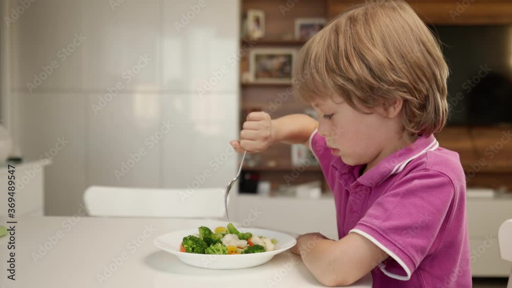 Boy tries to eat a vegetables but dosen't like it and rejects the food. Healthy food concept. Children and vegetables Boy tries to eat a vegetables but dosen't like it and rejects the food. Healthy food concept. Children and vegetables