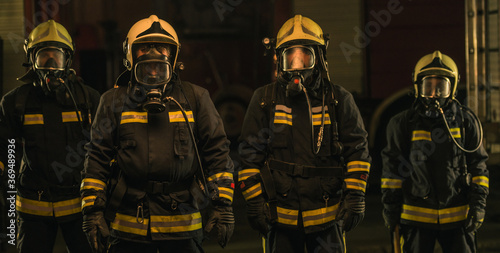 Group of firefighters in uniform posing inside the fire department's garage