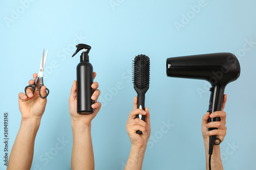 Female and male hands hold hairdressing tools on blue background