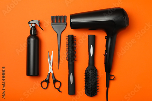 Flat lay with hairdresser accessories on orange background, top view