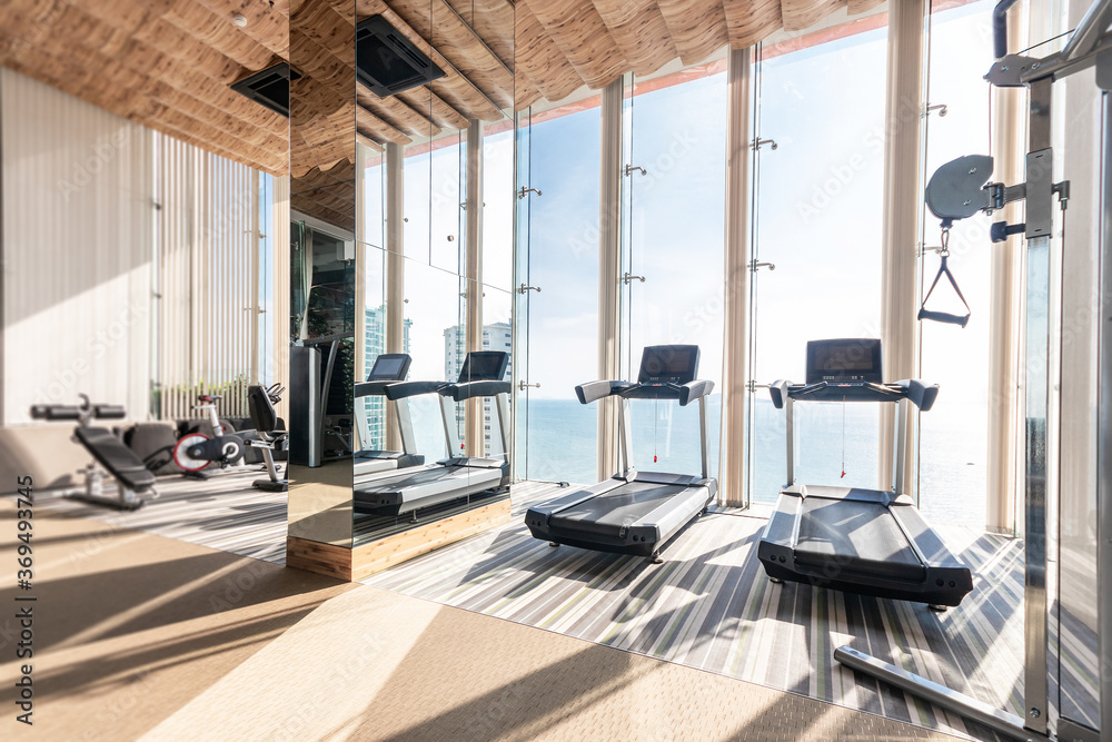 Gym fitness and Treadmill equipment at sky sea view and sunlight on top modern condominium overlooks the sea The sun s rays penetrated the big window into the luxury gym. Stock