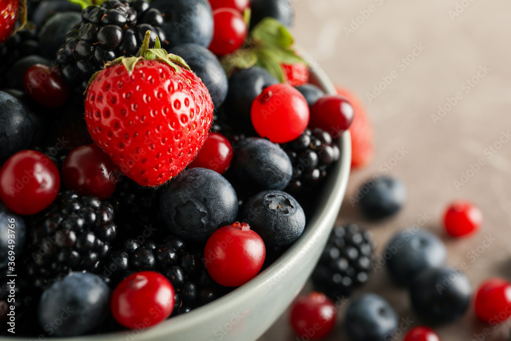 Bowl with fresh berries on gray table, close up Bowl with fresh berries on gray table, close up