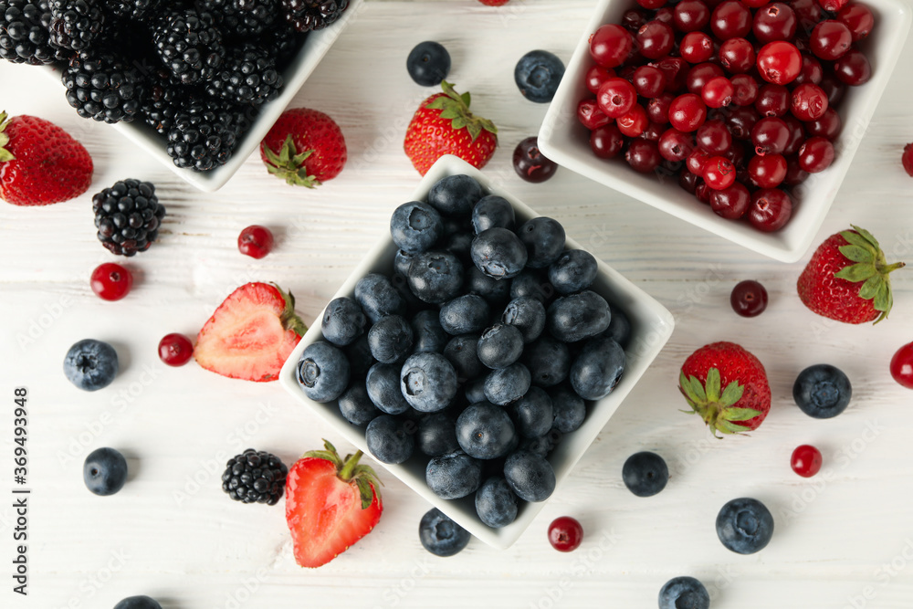 Bowls with berries on white wooden background, top view Bowls with berries on white wooden background, top view