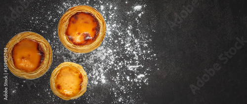 Принти на полотні top view of three tasteful egg tarts and wheat flour on dark grey texture backgr