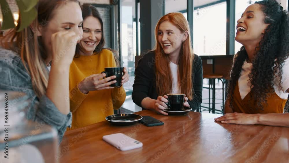 Group of female friends chatting at a cafe. Four women meeting in a coffee shop and talking.
