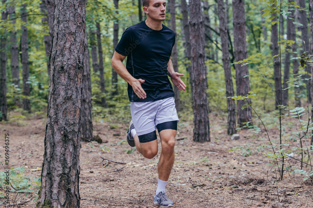 Full-length picture of an attractive male athlete running in the woods Full-length picture of an attractive male athlete running in the woods