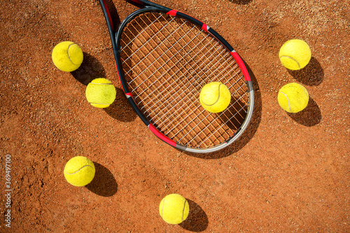Racket and scattered tennis balls on the court © Andrii 