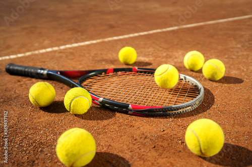 Racket and scattered tennis balls on the court © Andrii 