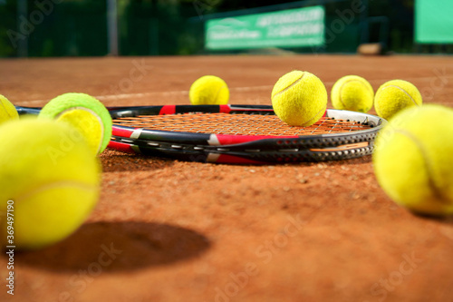 Racket and scattered tennis balls on the court © Andrii 