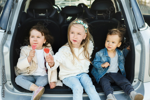 Little kids sitting in a car's trunk before a road trip
