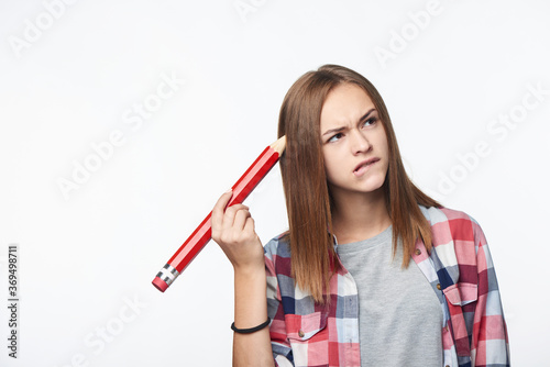 Contemplating girl scratching her head with big pencil