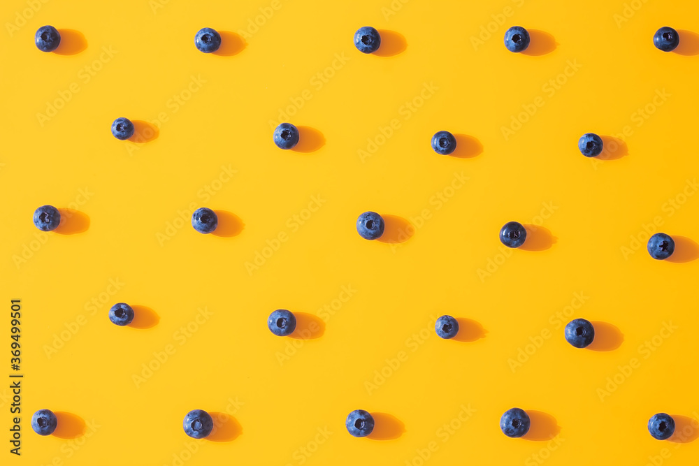 Seamless pattern with fresh sweet blueberry fruit on colorful yellow background. Dessert healthy food concept. Raw summer diet. Delicious nature vegetarian ingredient. Flat lay, minimal style