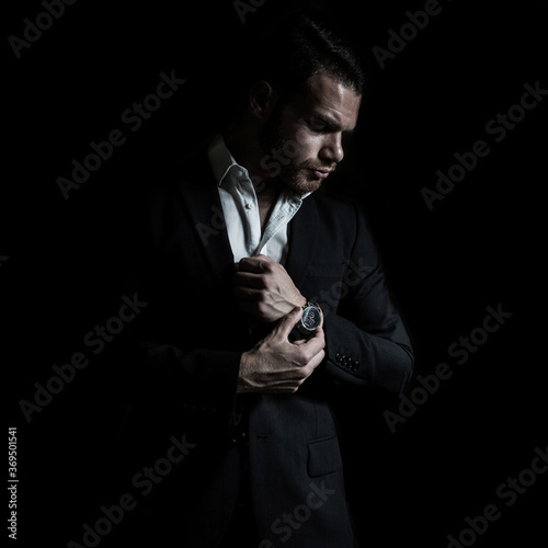 Business portrait of a young caucasian man in a black classic suit on a black background. 