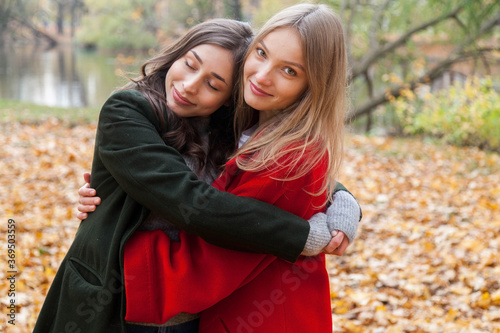 Two girls hugging in the autumn park