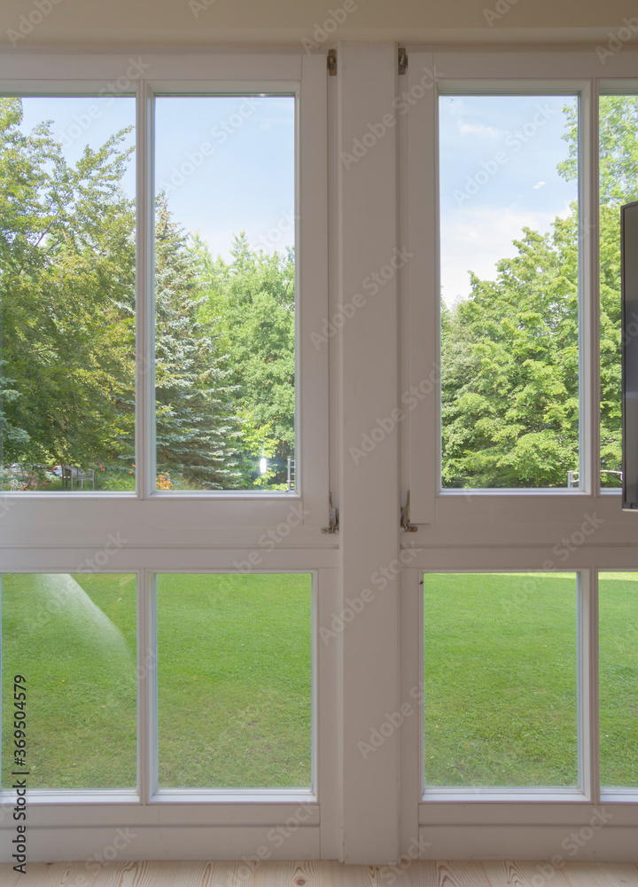 view of the window in the room on a green park on a sunny summer day view of the window in the room on a green park on a sunny summer day