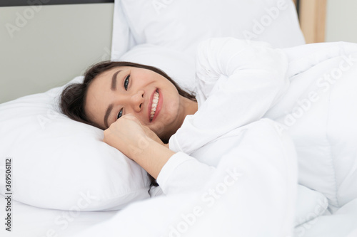 Young Woman Sleeping In Bed. Portrait Of Beautiful Female Resting On Comfortable Bed With Pillows in the morning. Happy woman sleeping on a pillow in bed and smiling. Pretty young girl on white bed.