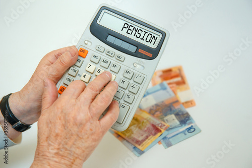 An elderly woman holds a calculator in her hands and calculates expenses.