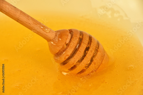 Close up wooden dipper in honey bowl