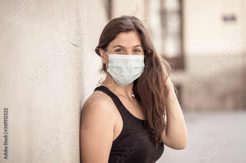 Portrait of attractive young happy woman with protective surgical face mask in public spaces © SB Arts Media