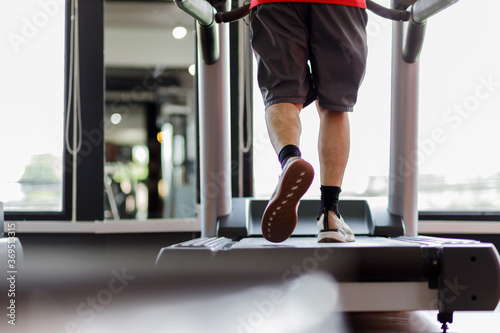 Close up foot sneakers Fitness man running on track treadmill, Man with muscular legs in exercise gym.