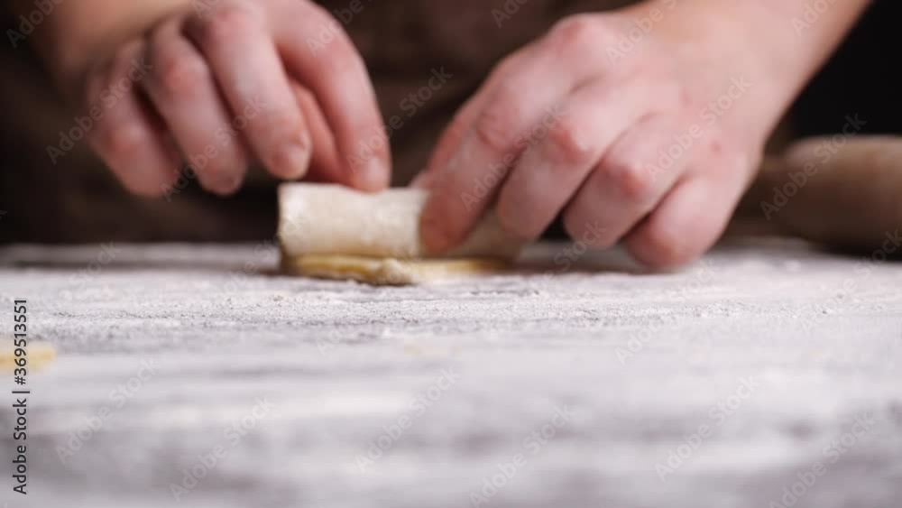 Anonymous female rolling sweet cookie from dough on table covered with flour in kitchen Anonymous female rolling sweet cookie from dough on table covered with flour in kitchen