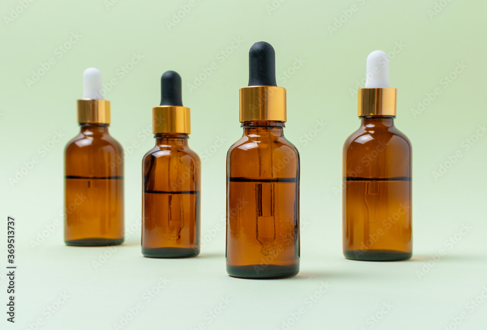Mock up glass cosmetic brown bottles with a pipette on a mint background.