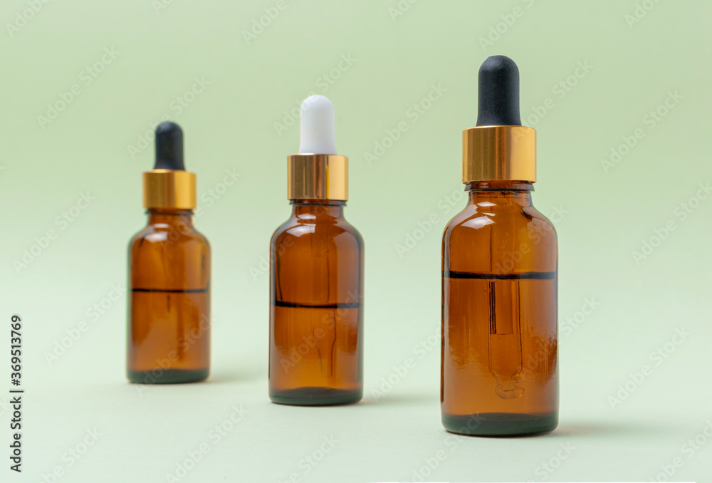 Mock up glass cosmetic brown bottles with a pipette on a mint background.