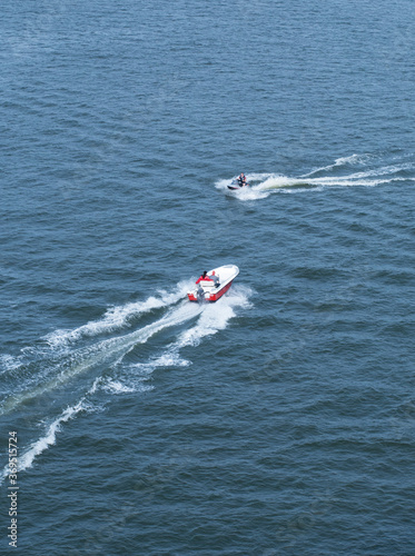 Motor boat and a water scooter are moving towards each other on the sea