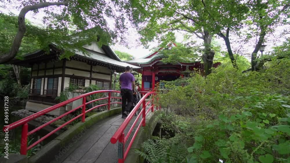 A father with his son cross the bridge in a Shinto temple. These bridges are believed to mark the boundary between the earthly and the spiritual world. Kichijojii Park, Tokyo, Japan. Slow motion. A father with his son cross the bridge in a Shinto temple. These bridges are believed to mark the boundary between the earthly and the spiritual world. Kichijojii Park, Tokyo, Japan. Slow motion.
