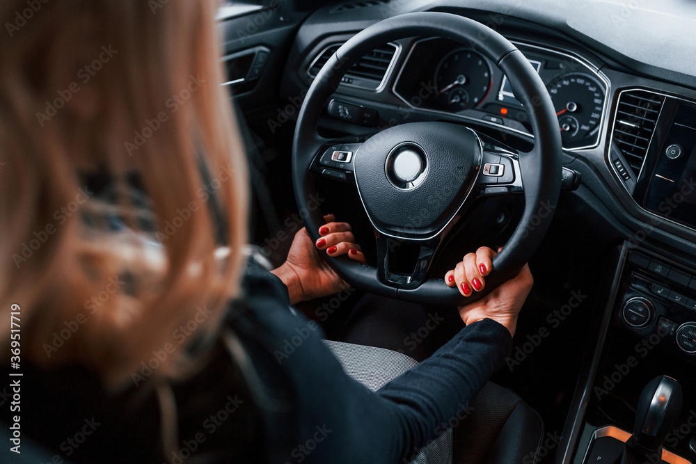 Rear view of beautiful blonde in elegant clothes that sitting inside of modern car