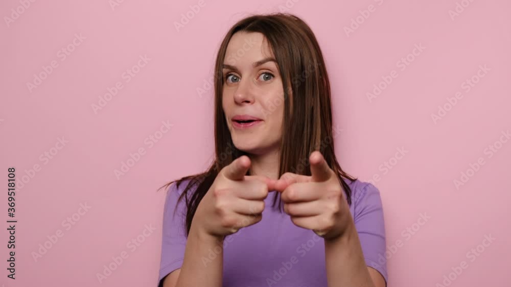 Portrait of amazed funny young woman pointing finger to camera, looking big eyes surprised expression, girl shocked by sudden success, dressed in purple t-shirt, isolated on pink studio background Portrait of amazed funny young woman pointing finger to camera, looking big eyes surprised expression, girl shocked by sudden success, dressed in purple t-shirt, isolated on pink studio background